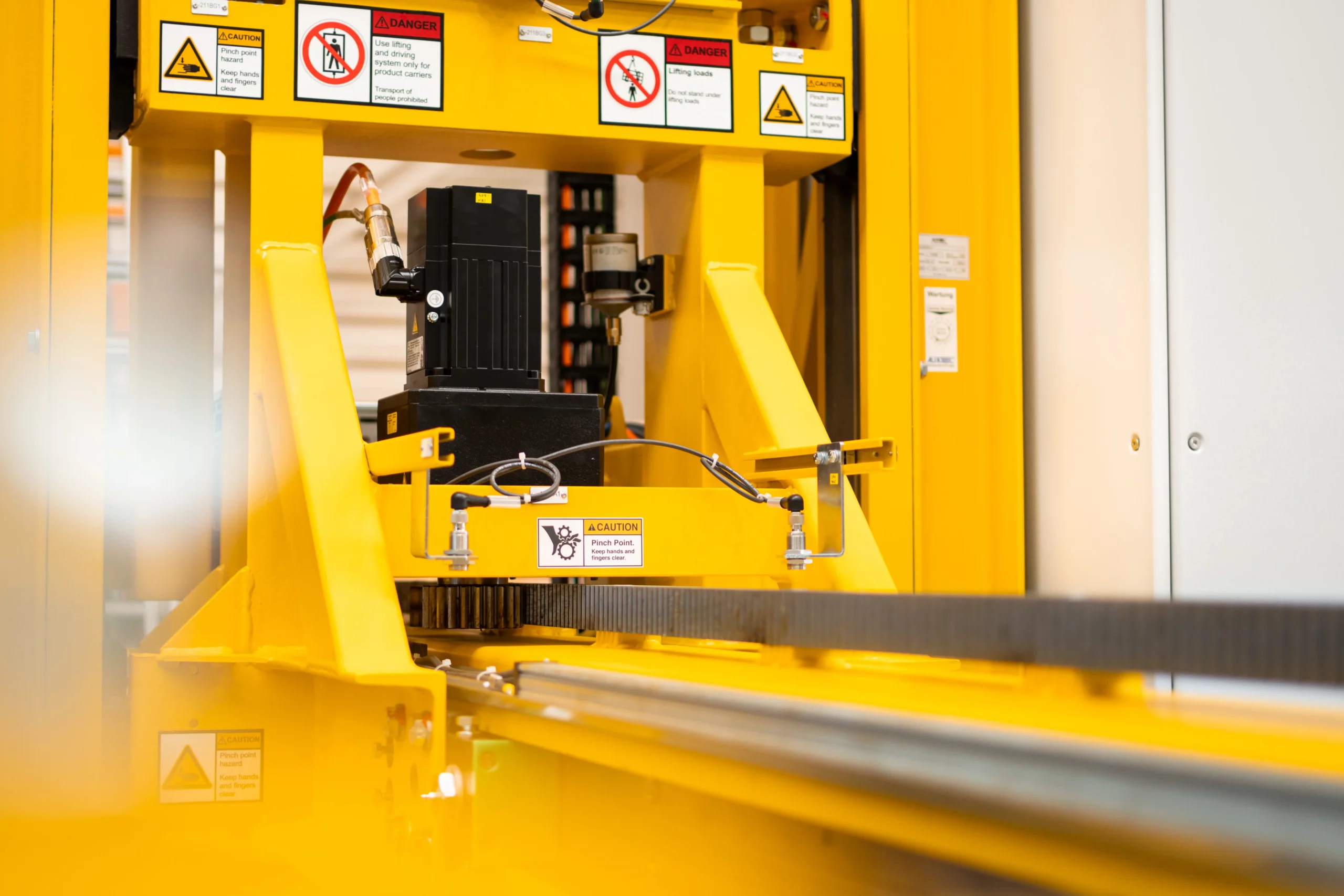 Präzise Antriebstechnik und Führungssysteme für Fördersysteme von ALFATEC Antriebseinheit und Führung eines Fördersystems mit Motor und Zahnstange in industrieller Anwendung